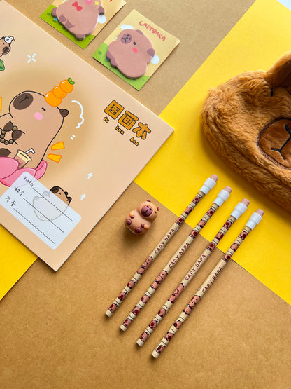 Close up of capybara themed pencils, sticky notes, and a fuzzy brown plush pencil pouch on a yellow background.