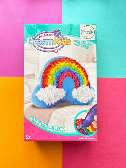 DreamKids Rainbow Pillow DIY craft kit box on a vibrant pink, green, and orange color block background.